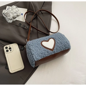 Détail du sac seau en peluche bleue avec écusson cœur blanc et garniture en cuir marron