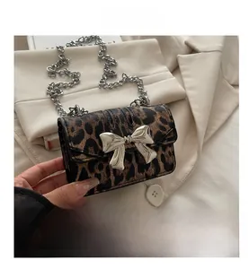 Detail of leopard print crossbody bag featuring large silver metal bow clasp and chain strap