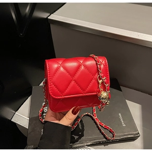Detailed view of red quilted mini bag with golden chain strap and hollow metal ball