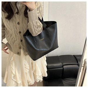 Detail of black leather tote bag with gold logo paired with an autumn knit sweater