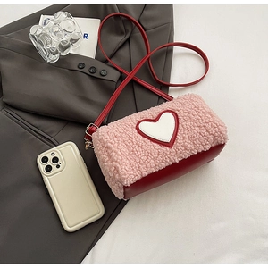 Détail du sac bandoulière en polaire rose avec finitions en cuir rouge et motif cœur