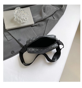 Top view of dark grey monogram crossbody bag with adjustable strap on white background
