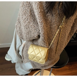 Detailed view of mini gold quilted crossbody bag with metal chain strap on model