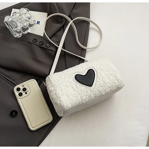 Détail du sac en polaire blanche avec un écusson en cuir noir en forme de cœur