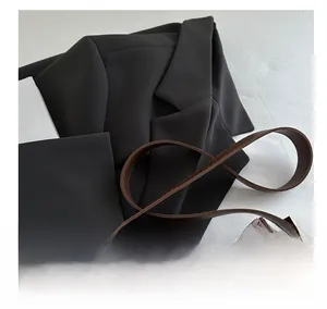 Détail d'un sac à main en cuir marron assorti à un blazer noir pour un look de bureau