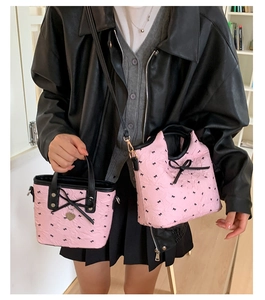 Detail of pink mini tote bag with black bow, heart charm, and textured pleats