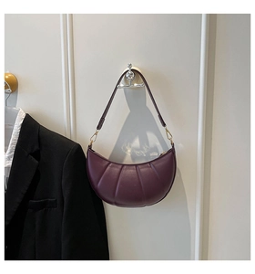 Close-up of a burgundy crescent bag with vertical quilting and golden metal hooks
