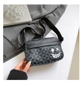 Detail of crossbody bag with black geometric pattern and white graffiti smiley face
