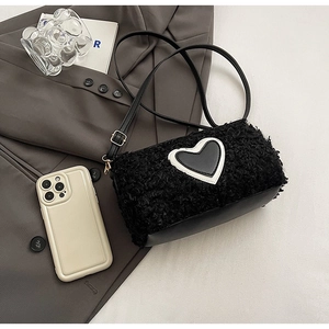 Détail d'un sac bandoulière en peluche noire avec base en cuir et patch cœur