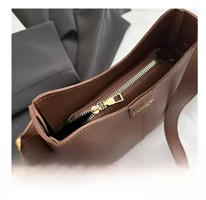 Détail de la fermeture éclair en métal doré et des coutures sur un sac en cuir marron