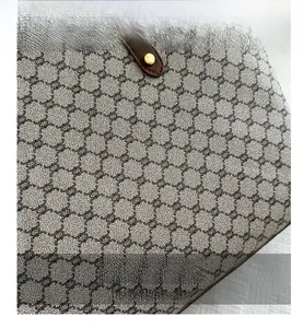 Detail of monogram pattern on high-density fabric with gold metal stud and brown leather trim