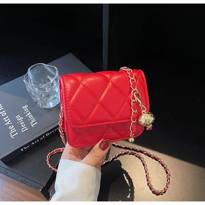 Detailed view of red quilted mini bag with gold chain and textured metal ball charm