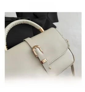 Detail of off-white lychee grain tote bag featuring gold buckle and rounded handle