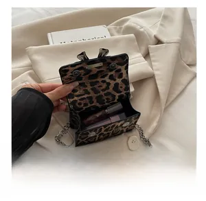 Internal view of leopard print mini chain bag showing storage capacity for lipsticks