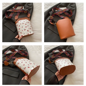 Detailed views of printed cylinder bucket bag with cherry pattern and ethnic shoulder strap