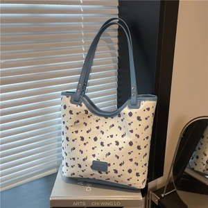 Sac cabas à fleurs violettes avec anses bleues exposé dans un cadre moderne