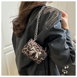 Close-up of leopard print crossbody bag featuring a silver metal bow and chain strap