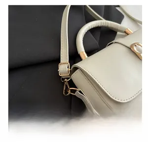 Detail of adjustable strap and golden metal buckle on a beige faux leather handbag