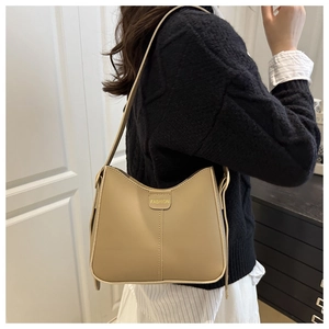 Détail du sac seau beige minimaliste avec inscription FASHION et couture verticale