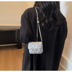 Detail of silver quilted mini crossbody bag with metal chain strap on model