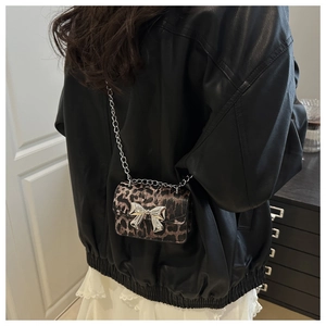 Detailed view of leopard print mini bag with silver bow and chain strap on shoulder