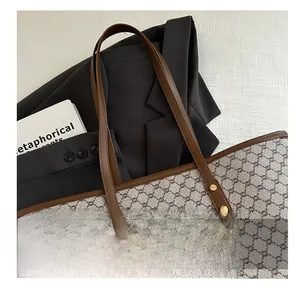 Detailed macro view of monogram canvas tote with leather handle and gold rivet hardware