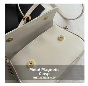 Detailed close-up of the magnetic clasp and smooth cream leather on this crossbody bag