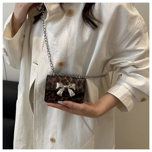 Detailed view of leopard print mini crossbody bag with silver bow and metal chain strap