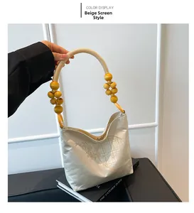 Dettaglio della borsa a secchiello ricamata beige con motivo a paravento cinese e manico in corda