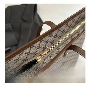 Macro shot of smooth gold zipper and retro monogram canvas with brown leather trim