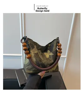 Dettaglio della borsa vintage in tessuto con stampa a farfalla dorata e manico di perle