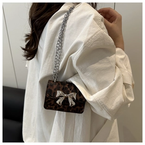 Mini leopard print crossbody bag with silver bow buckle worn over a white dress