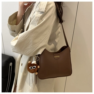 Détail du sac à bandoulière marron vintage avec logo et charm ours en peluche