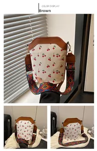 Detail of white cherry print bucket bag with colorful geometric woven wide shoulder strap
