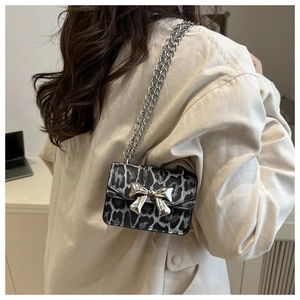 Close-up of leopard print mini square bag with large silver metal bow and chain strap