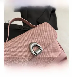 Dettaglio della patta intrecciata rosa e fibbia a ferro di cavallo sulla borsa