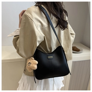 Détail d'un sac à bandoulière noir en similicuir avec un joli pendentif ours en peluche beige