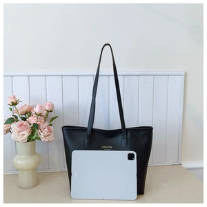Large black leather tote bag shown with an 11-inch tablet to demonstrate its spacious capacity