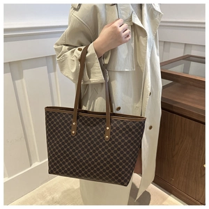 Detail of vintage brown monogram tote bag with leather strap and golden rivets