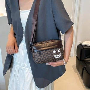 Brown geometric patterned crossbody bag with street style graffiti face and wide strap