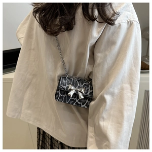 Close-up of a mini leopard print square bag with silver metal bow and chain strap