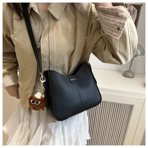 Détail du sac seau en cuir noir avec logo FASHION en métal et pendentif peluche