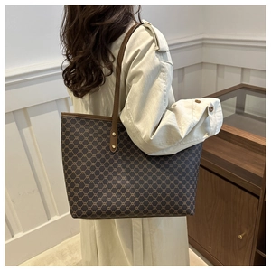 Detail of a large brown tote bag with vintage chain patterns and gold rivet hardware