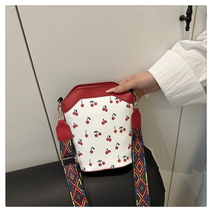 Close-up of cherry pattern bucket bag with colorful ethnic geometric wide shoulder strap