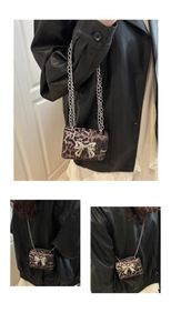 Detailed macro view of leopard print mini square bag with silver metal bow and chain strap