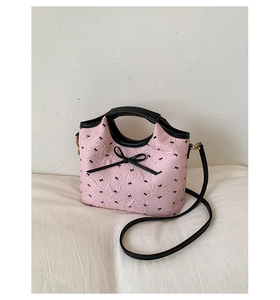 Dettaglio della borsa tote rosa a pois con finiture in pelle nera e fiocchi decorativi