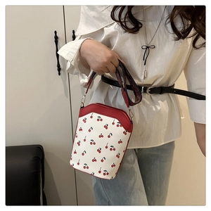Detail of cherry print handbag with wide geometric strap worn with casual outfit