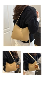 Détail du sac seau beige avec plaque FASHION et breloque monstre en peluche marron