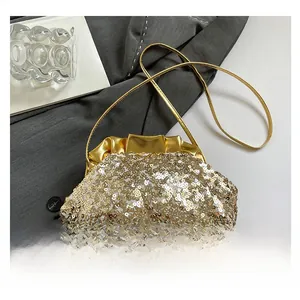 Close-up of luxury sequins clutch bag with gold chain on grey fabric background