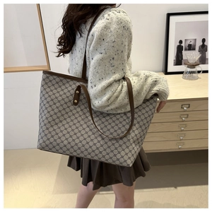 Lifestyle view of a large tote bag with vintage monogram and brown shoulder strap